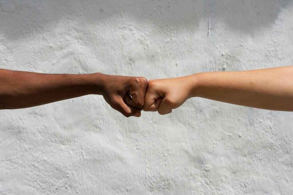 Two people bumping fists against a white wall